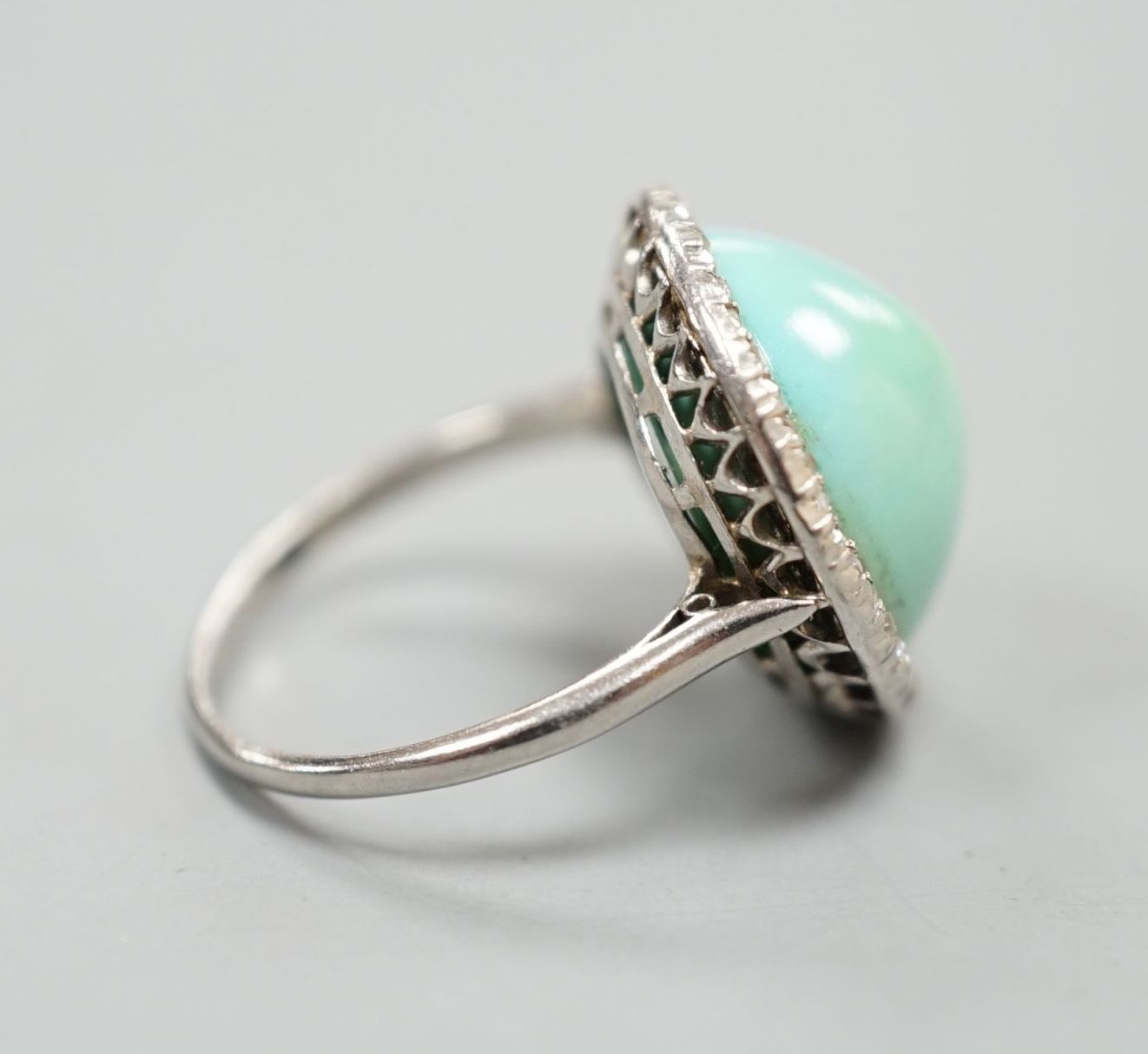 A white metal cabochon turquoise and diamond chip set dress ring, size J/K, gross 6.9 grams.